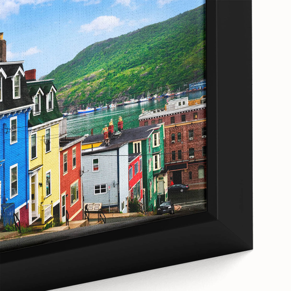 Close-up of a textured black wall art featuring a colorful Newfoundland scenery on a framed canvas.