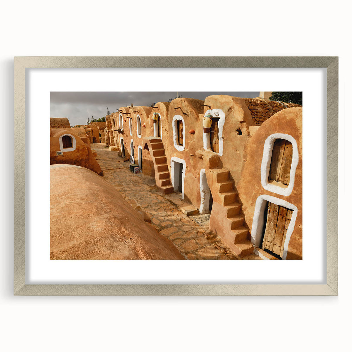 Textured art print of an abstract Tunisian landscape in earthy tones, framed in silver, ideal for bedroom art.