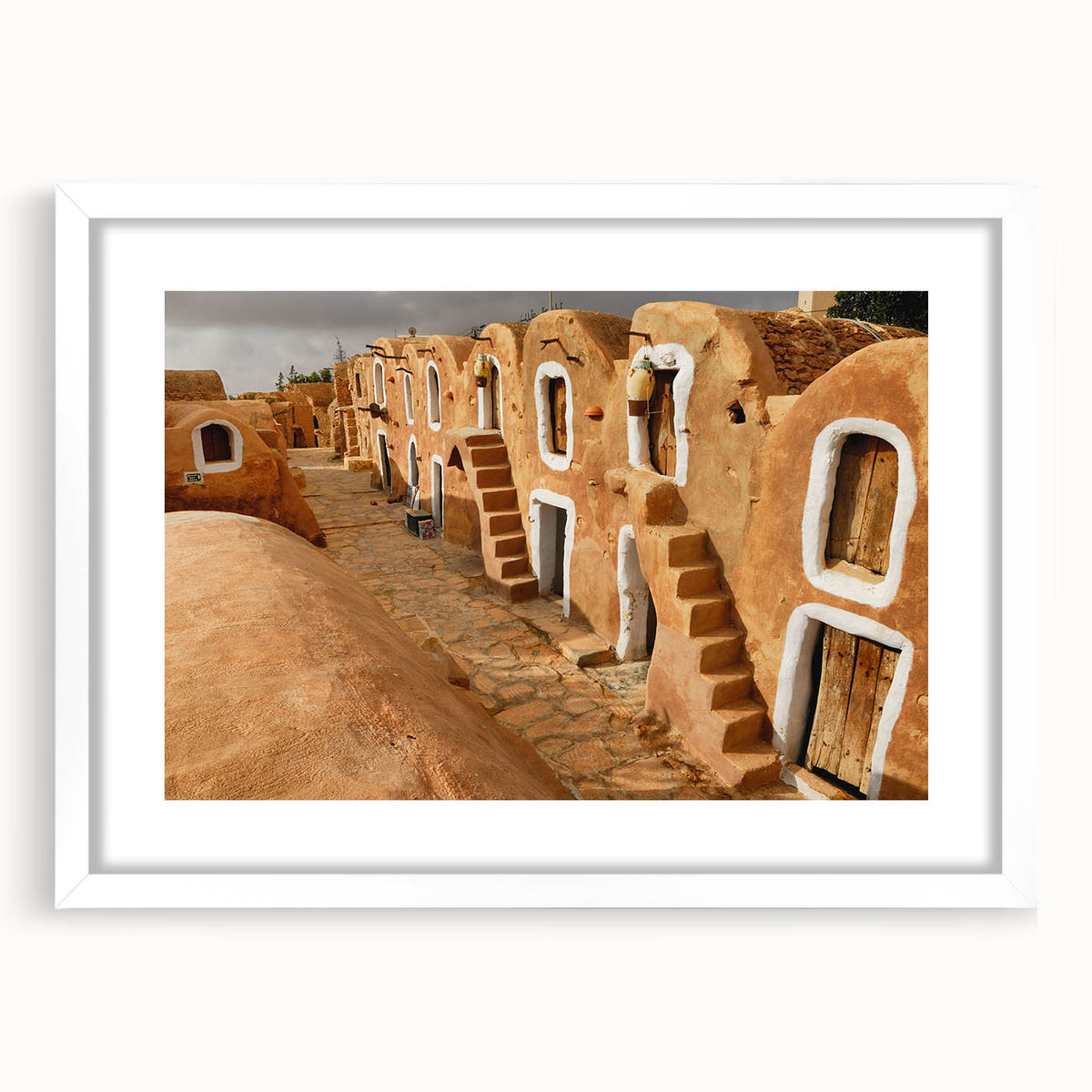 Abstract art print depicting a Tunisian landscape in earthy tones on a framed white mat, suitable for dining room decor.