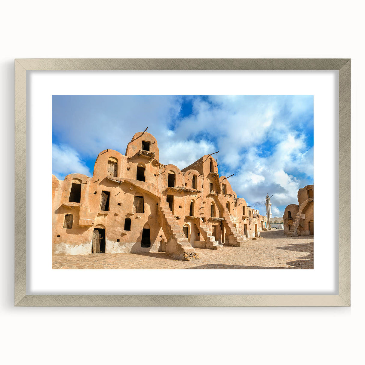 Textured abstract art print depicting a Tunisian landscape in earth tones, framed in silver, suitable for bedroom decor.