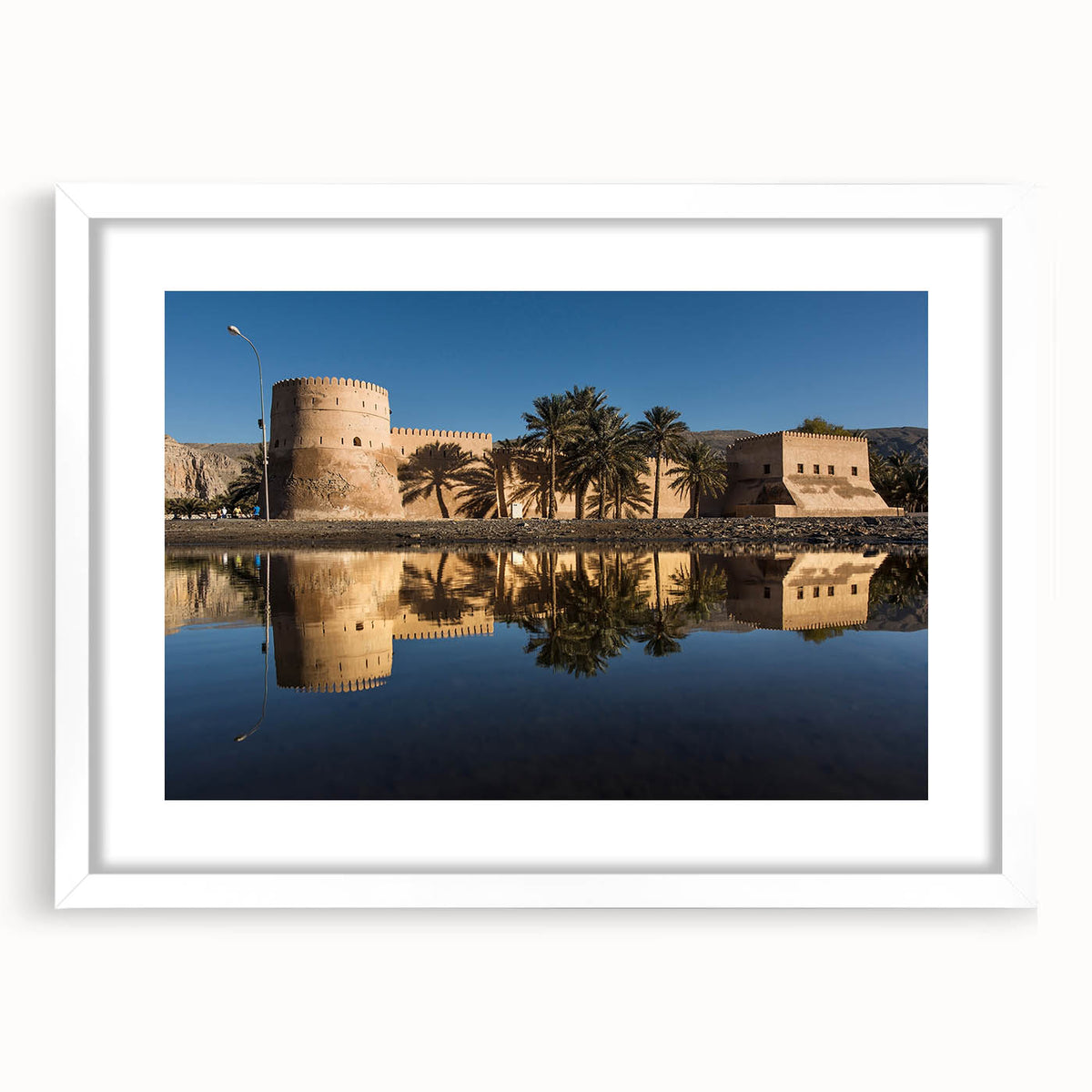 Abstract art print featuring a stylized Oman scenery in earth tones on a white-matted frame, suitable for dining room decor.