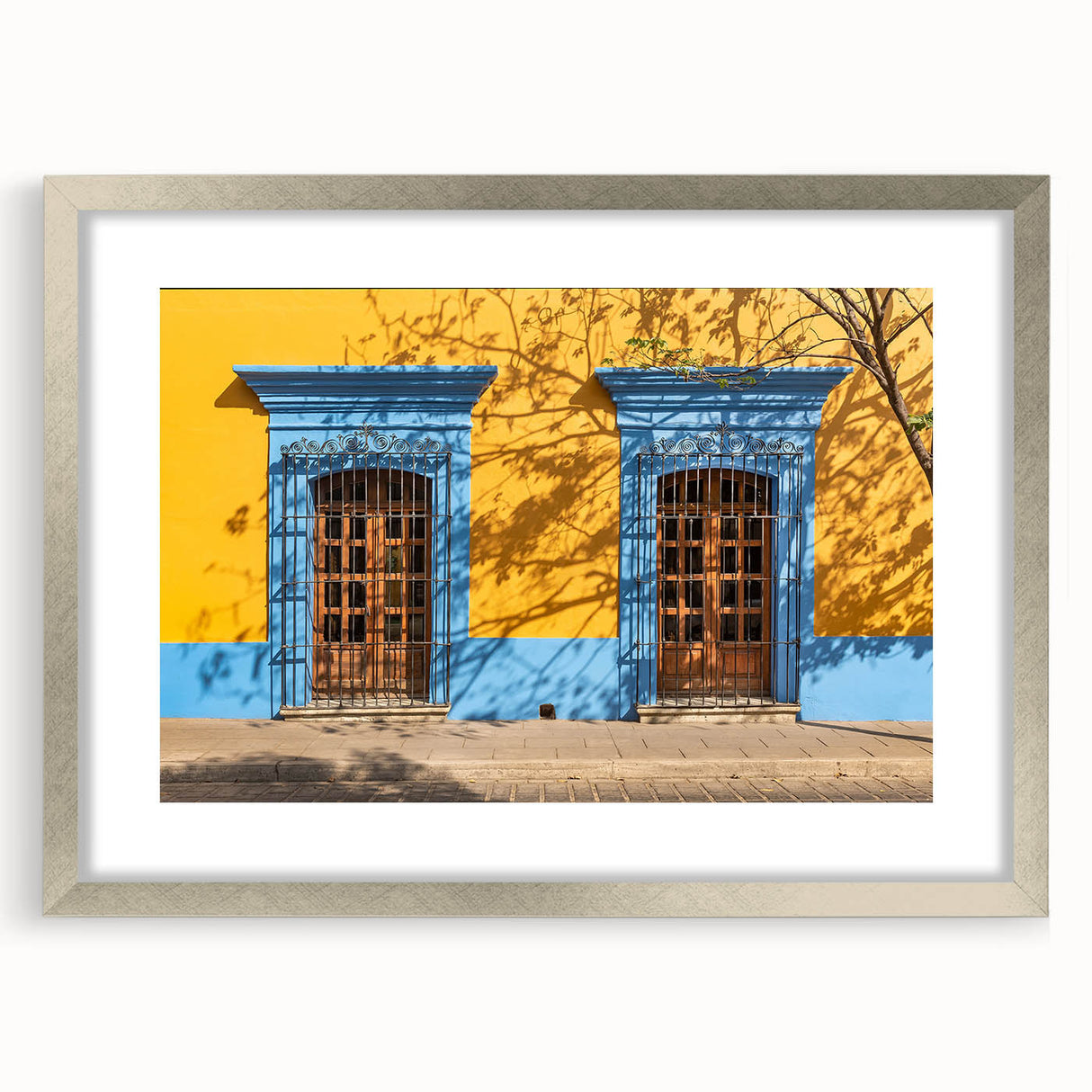 Textured art depicting abstract scenery of Oaxaca in muted earth tones, framed with a silver mat, ideal for bedroom decor.