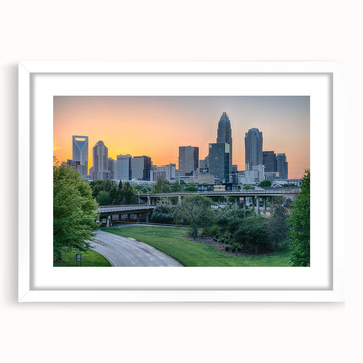 Abstract art print of Charlotte skyline in muted blue and gray tones on a framed white mat, ideal for dining room decor.