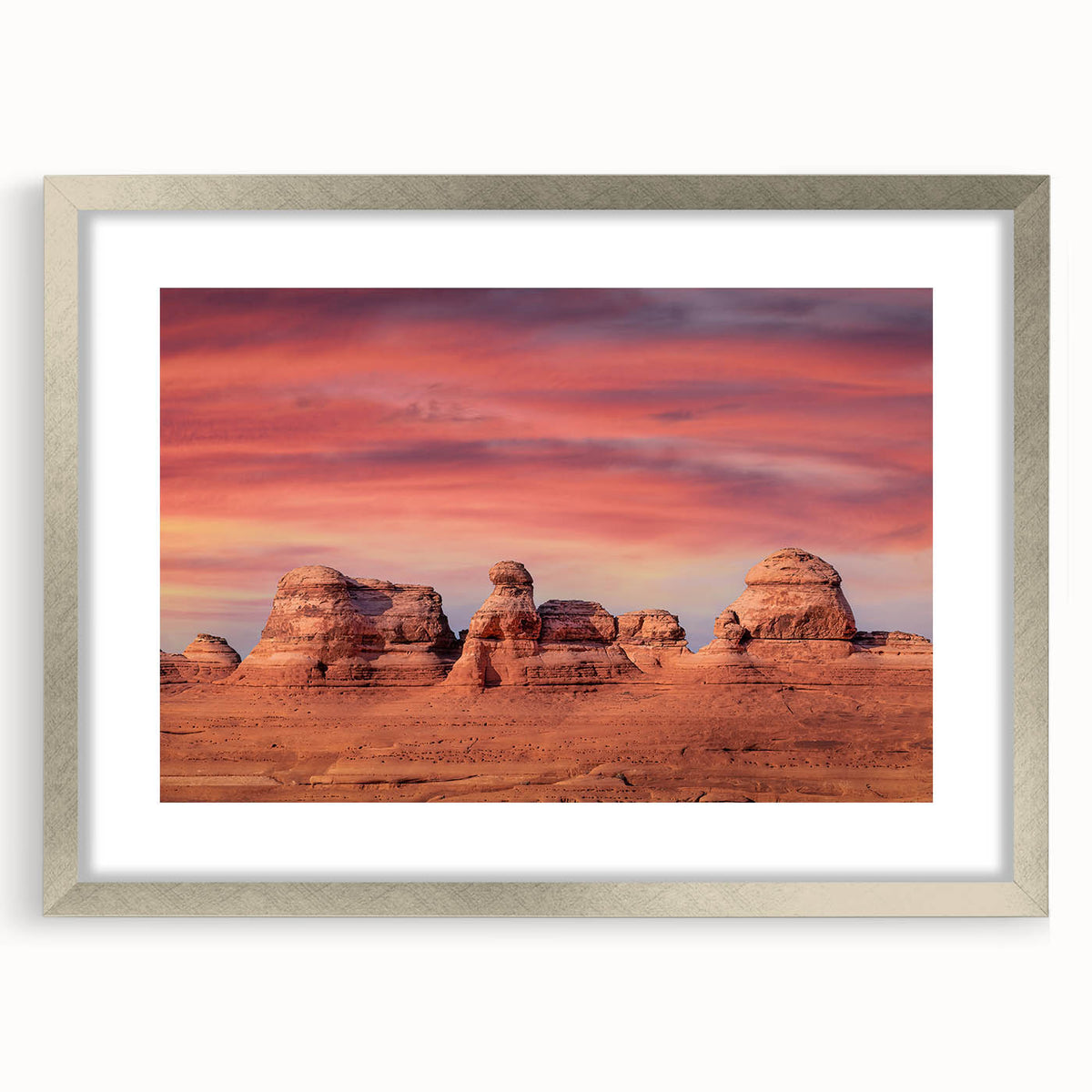 Textured art depicting Arches National Park in muted earth tones on a framed silver mat, suitable for bedroom decor.