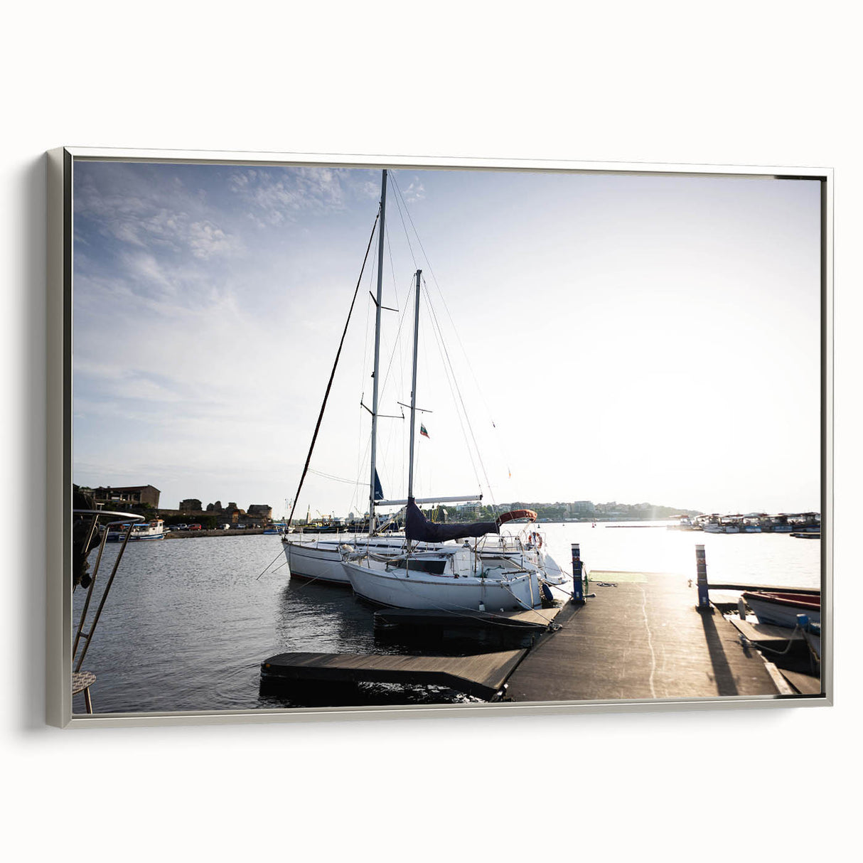 Framed canvas wall art showcasing a serene harbor landscape design in silver tones, perfect for enhancing modern home decor. The piece captures tranquil water reflections and a vibrant sky, adding elegance to any room setting.