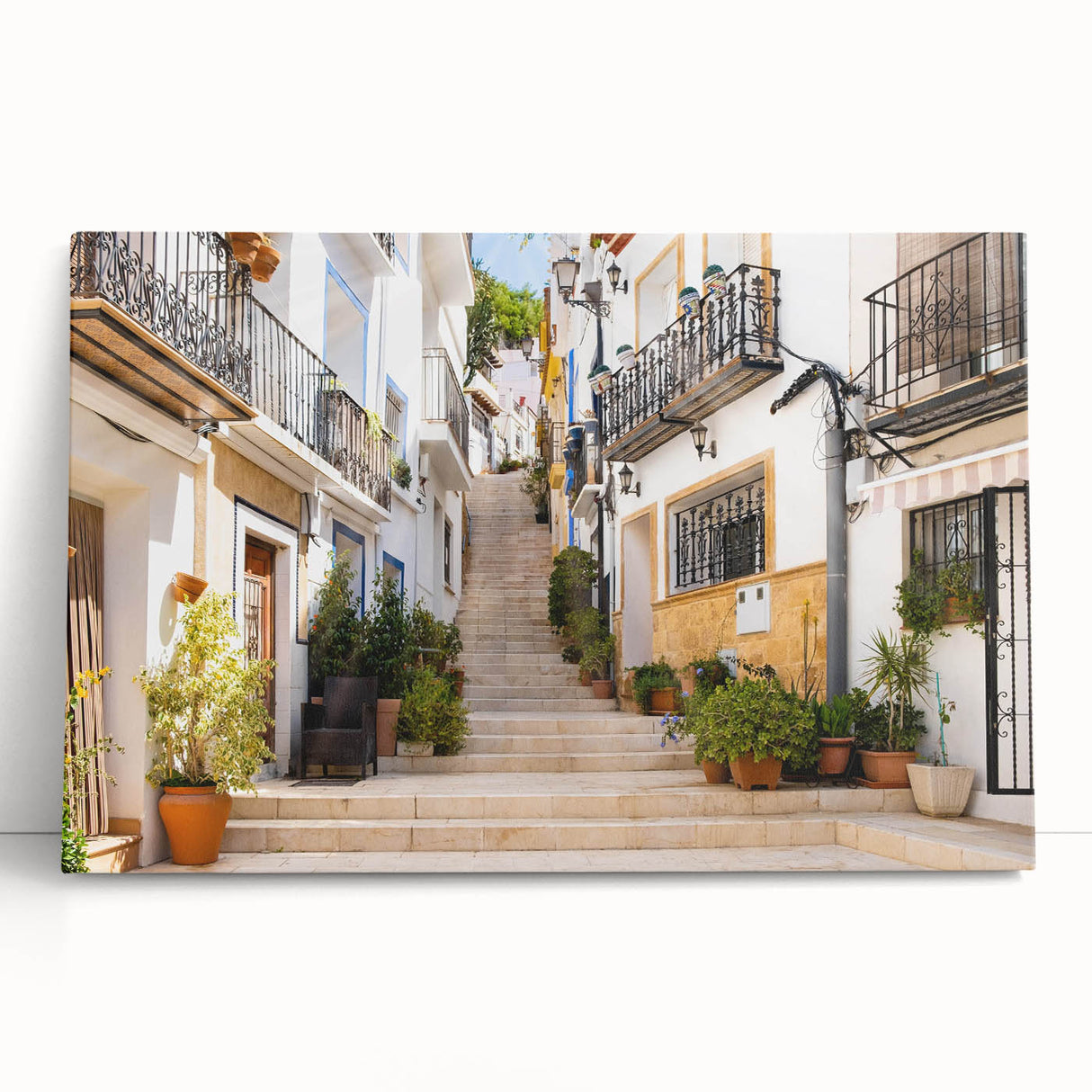 Stretched canvas wall art featuring a vibrant landscape design with colorful streets and abstract elements, leaning against a neutral wall in a modern setting.