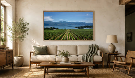 Countryside vineyard landscape canvas in green and blue, natural wood frame above oatmeal linen sofa in modern farmhouse living room.
