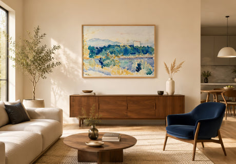 Impressionist coastal hillside landscape in navy, green, and gold, framed above a walnut sideboard in a modern open-concept living room.