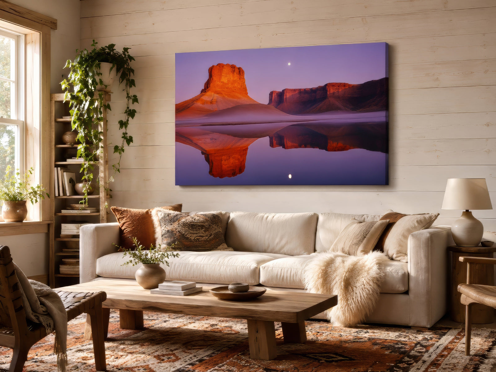 Canvas of red rock mesa reflected in calm water at dusk with purple sky, above cream sofa in rustic living room