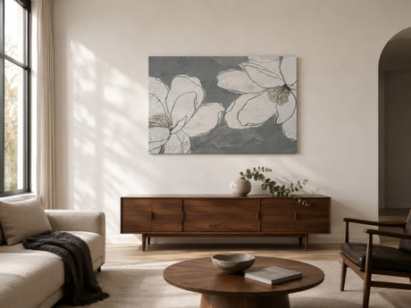 Grey and white magnolia floral canvas over walnut sideboard in a calm Scandinavian living room with linen sofa