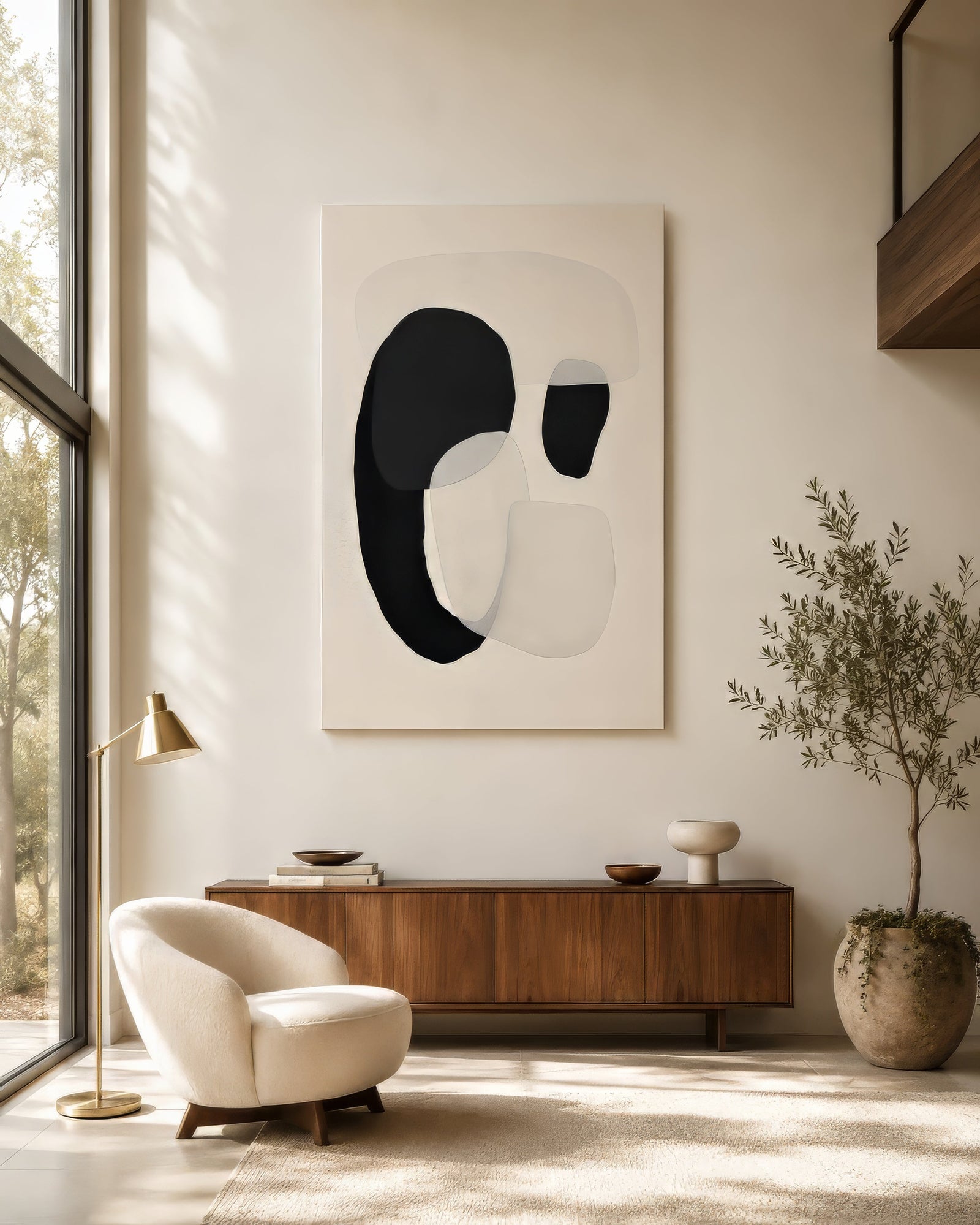 Black and white abstract canvas with rounded organic forms hung in a bright minimalist living room with walnut sideboard and boucle chair