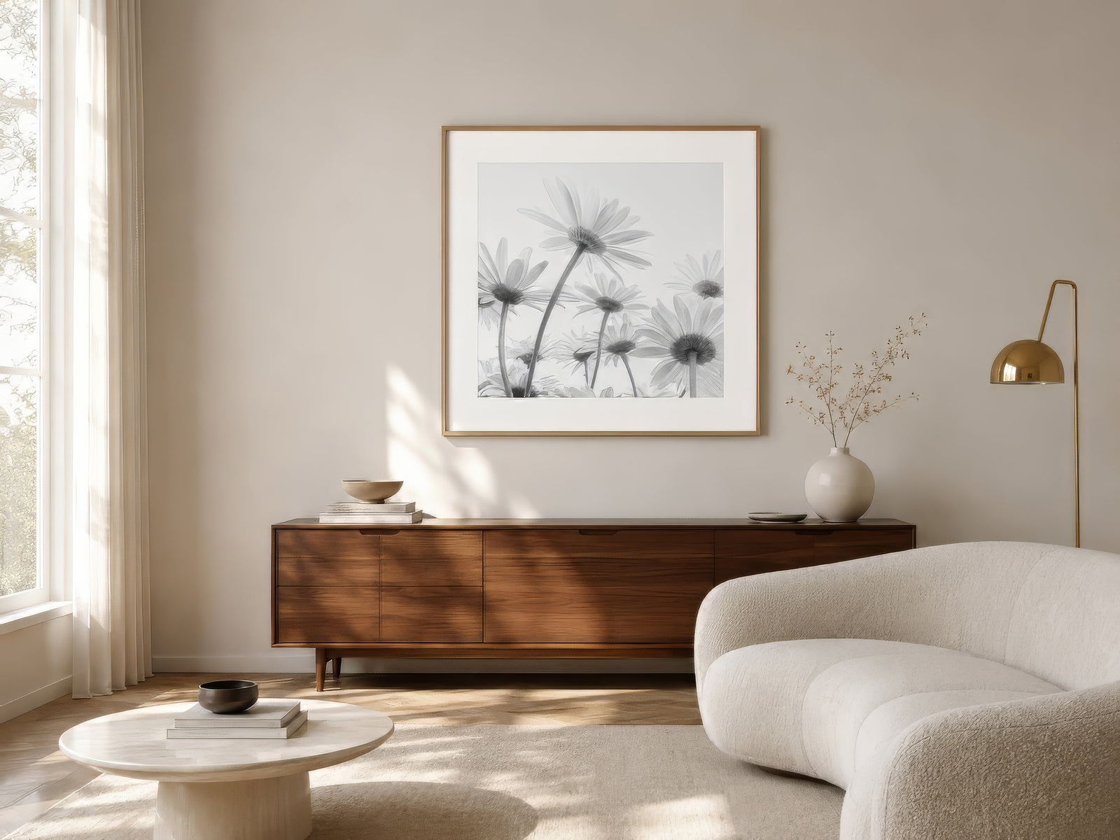 Monochrome daisy photography in oak frame above walnut credenza in airy neutral living room with daylight