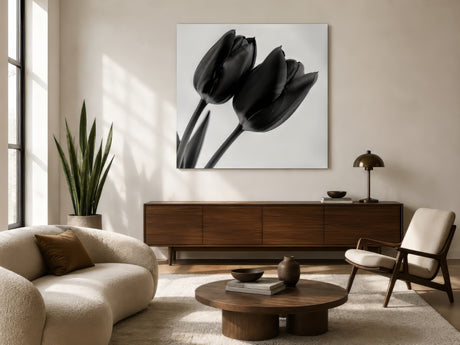 Monochrome tulip photograph in white frame above walnut sideboard, boucle sofa and round wood table in modern living room