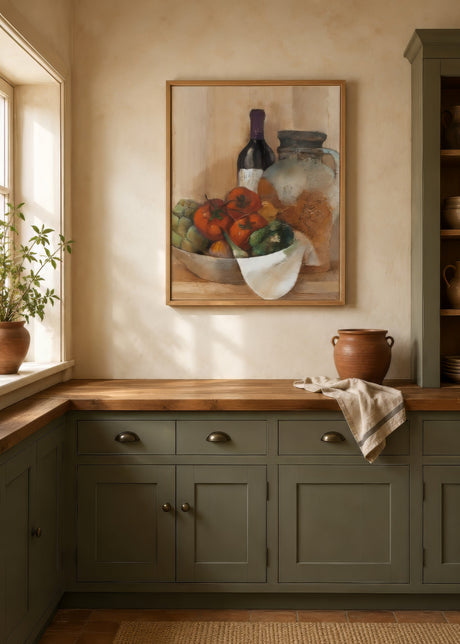 Food still-life painting of tomatoes and wine in warm tones, oak frame above counter in a sage-green farmhouse kitchen.