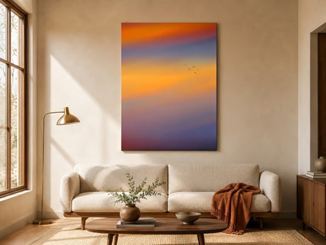 Large abstract sunset painting in orange and lavender hues above a cream boucle sofa in a warm minimalist living room