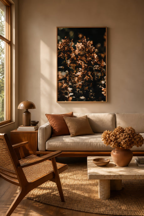 Nature-inspired wall art of dried autumn flowers in bronze and brown, framed above an oak sideboard in a sunlit linen-and-jute living room.