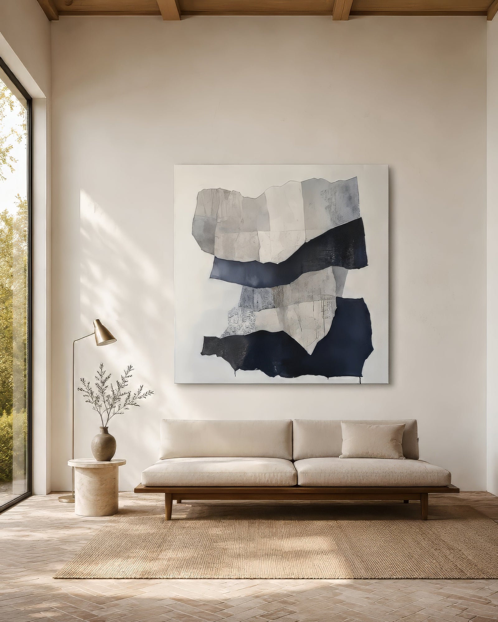 Large modern abstract canvas with navy and grey collage forms above a cream sofa in an airy oak-floored living room