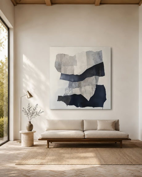 Large modern abstract canvas with navy and grey collage forms above a cream sofa in an airy oak-floored living room