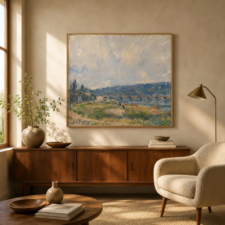 Impressionist river and bridge landscape print in green and blue tones, oak-framed above linen sofa in warm-plaster living room.