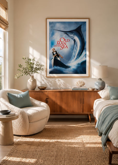Old Man and the Sea movie poster art with leaping blue marlin, framed above linen headboard in airy coastal bedroom.