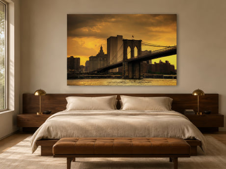 Framed Brooklyn Bridge print in warm amber tones hung above a linen bed with walnut nightstands in a calm bedroom.