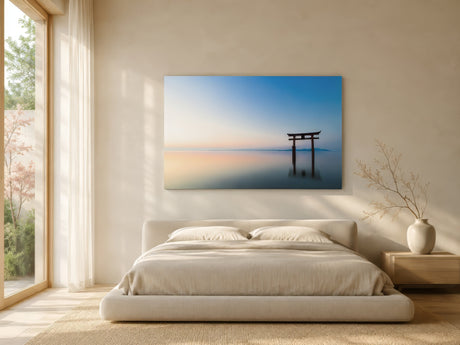 Photographic canvas of a torii gate in still water with pastel sky, above a platform bed in a bright minimalist bedroom