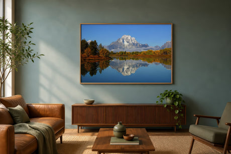Wide Andes mountain landscape print in cool blues and gold above a leather sofa in a calm neutral living room.