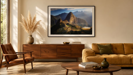 Machu Picchu Andes landscape photograph in warm gold and green tones, framed above sofa in calm modern living room.