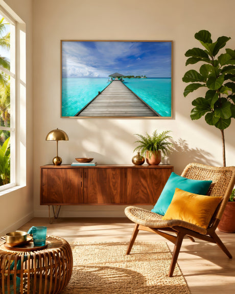 Tropical beach photograph of a wooden jetty over turquoise lagoon water, framed in light wood, in a sunlit rattan sunroom.