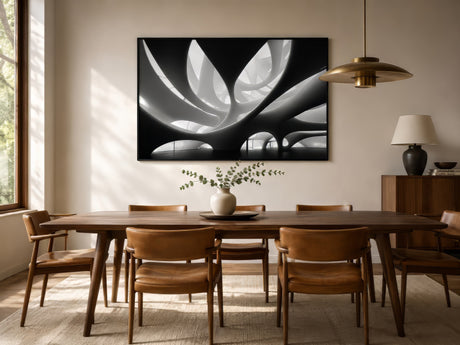 Black and white abstract floral canvas with white petals on black, framed above a walnut table in a modern dining room with brass pendant light.
