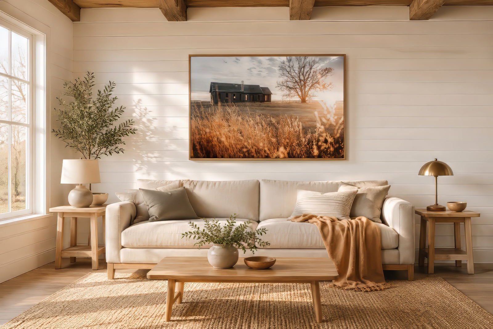 Vintage sepia-gold landscape print of a barn and tree in tall grass, light wood frame, above a linen sofa in a modern farmhouse living room.