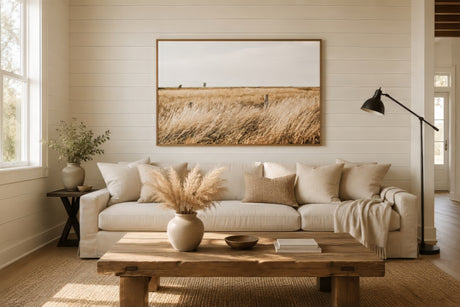 Golden wheat field landscape art in warm amber and ivory tones, framed above a cream sofa in a modern farmhouse living room.