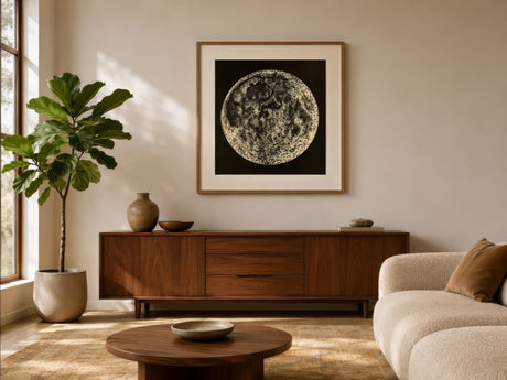 Black and white full moon fine art print in wood frame above wood sideboard in sunlit modern living room