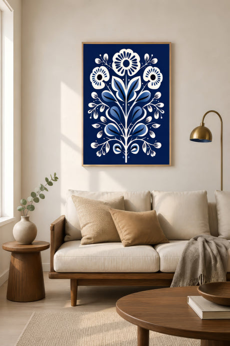 Scandinavian folk-art floral print in navy blue and white, light wood frame, above neutral sofa in airy living room.