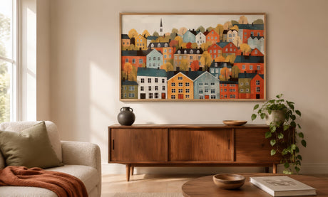 Naive folk-art painting of colorful Scandinavian harbor houses in amber and teal, framed above oak sideboard in warm Nordic living room.
