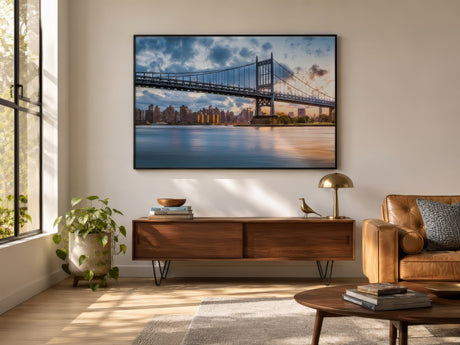 Golden sunset New York skyline and bridge print, framed in black above a walnut console in a warm modern living room.