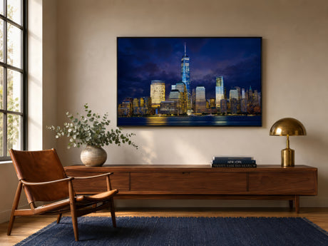 Lower Manhattan skyline canvas at dusk in indigo and gold, framed above a walnut console in a modern entryway.