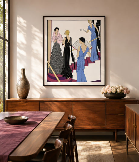Art Deco fashion print of women in blue and black gowns, black frame, above wood sideboard in warm dining room.