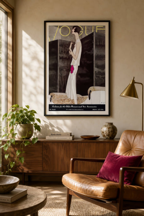 Vintage Vogue editorial poster in oak frame above neutral sofa, ivory and magenta tones, warm living room palette styling.