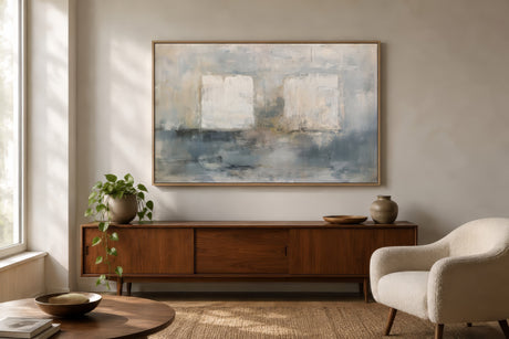 Minimalist blue and ivory abstract landscape canvas in wood frame above walnut sideboard in calm light-filled apartment living room.