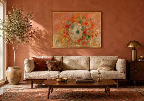 Vintage-style abstract floral print in coral, orange, and teal over a cream sofa in a warm terracotta modern living room.