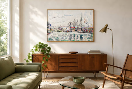 Impressionist coastal town and cathedral painting in oak frame above mid-century sideboard in a sunny green living room.