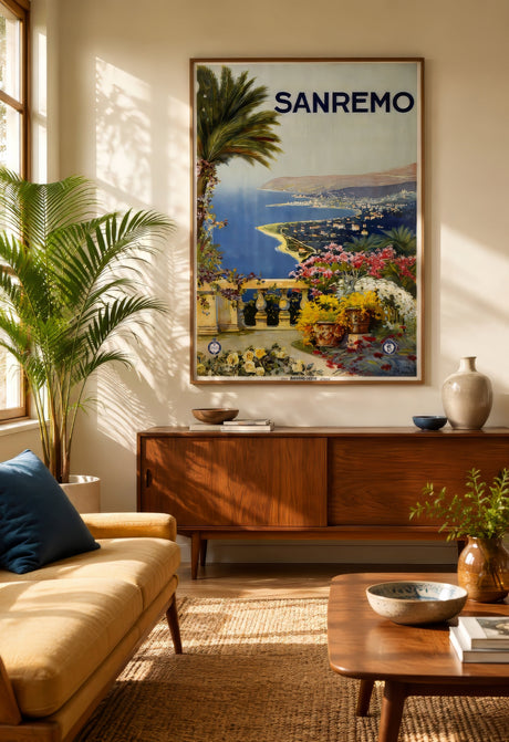 Retro Sanremo travel poster showing the Italian Riviera coast with blue sea and flowers, framed above a wood credenza in a warm neutral living room.
