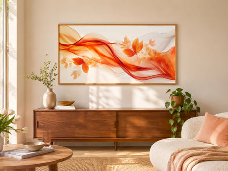 Abstract floral canvas with red and orange ribbons and autumn leaves, framed in light wood above a walnut console in a sunny living room.