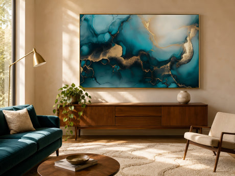 Teal and gold marbled abstract canvas in gold frame above charcoal sofa in warm neutral sunlit living room.