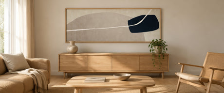 Neutral abstract canvas in beige and navy, slim oak frame, above a linen sofa in a calm Scandinavian living room.