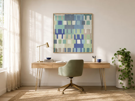 Geometric abstract wall art in blue, green, and beige squares above a wood desk in a bright modern home office.