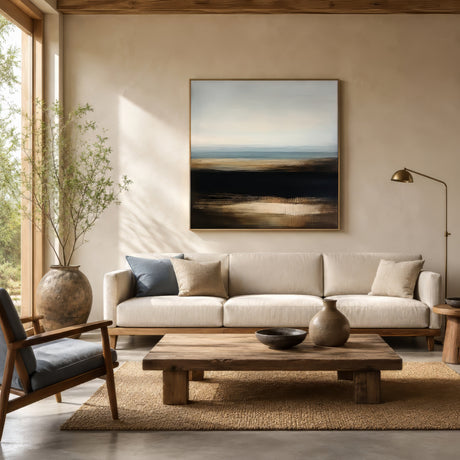 Abstract farmhouse landscape print in gold, black, and blue, framed above a linen sofa in a modern rustic living room.