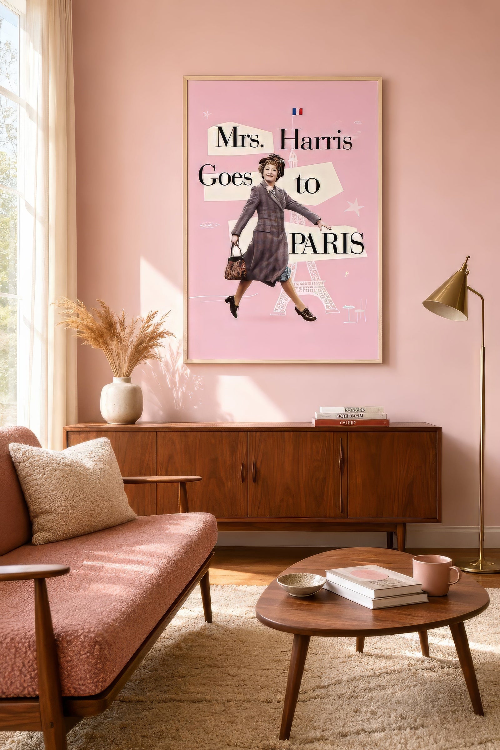 Vintage editorial Mrs. Harris Goes to Paris print in pink and grey, framed above a pink sofa in a calm modern living room.
