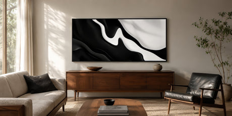 Framed black and white abstract skyline print in monochrome over wood sideboard, modern living room, glare-free picture light.